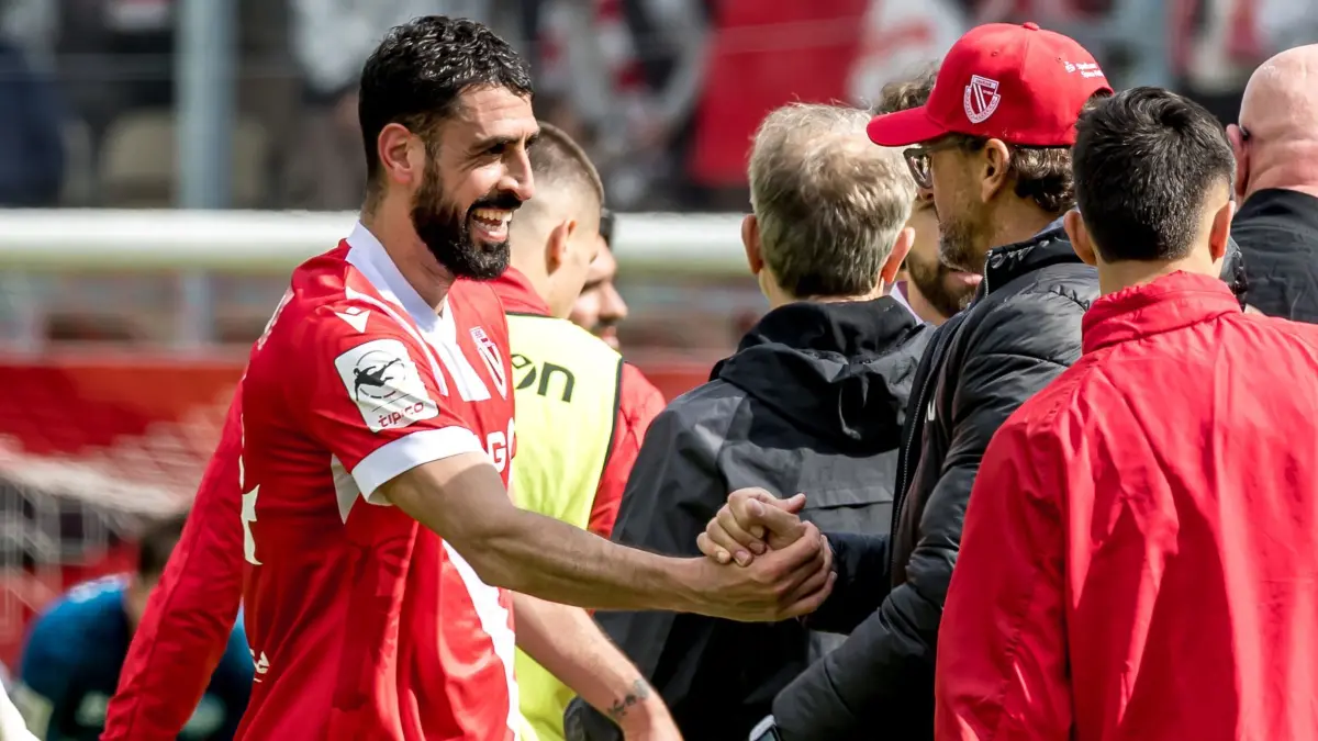 Energie Cottbus - SV Wehen Wiesbaden: 09.05.2026, Brandenburg, Cottbus: Fußball, Männer: 3. Liga, Energie Cottbus - SV Wehen Wiesbaden, 37. Spieltag, LEAG Energie Stadion. Tolga Cigerci (FC Energie Cottbus, l) und Trainer Claus-Dieter Wollitz (FC Energie Cottbus) geben sich nach Spielende die Hand. Foto: Frank Hammerschmidt/dpa +++ dpa-Bildfunk +++