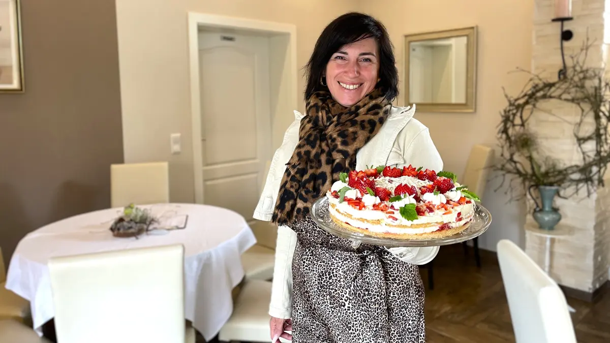 Roxana Trasper, Chefin des Café Roxy in Senftenberg, hält am 24.04.2026 eine Erdbeertorte in die Kamera.