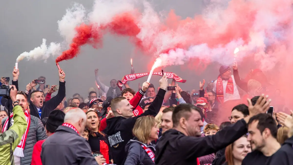 Jahn Regensburg - Energie Cottbus - Public Viewing in Cottbus: 16.05.2026, Brandenburg, Cottbus: Fußball, Männer: 3. Liga, Jahn Regensburg - Energie Cottbus, 38. Spieltag, Fans von Energie Cottbus jubeln mit Pyrotechnik. Sie feiern den Aufstieg ihrer Mannschaft in die 2. Bundesliga. Foto: Frank Hammerschmidt/dpa - ACHTUNG: Nur zur redaktionellen Verwendung im Zusammenhang mit der aktuellen Berichterstattung und nur mit vollständiger Nennung des vorstehenden Credits +++ dpa-Bildfunk +++