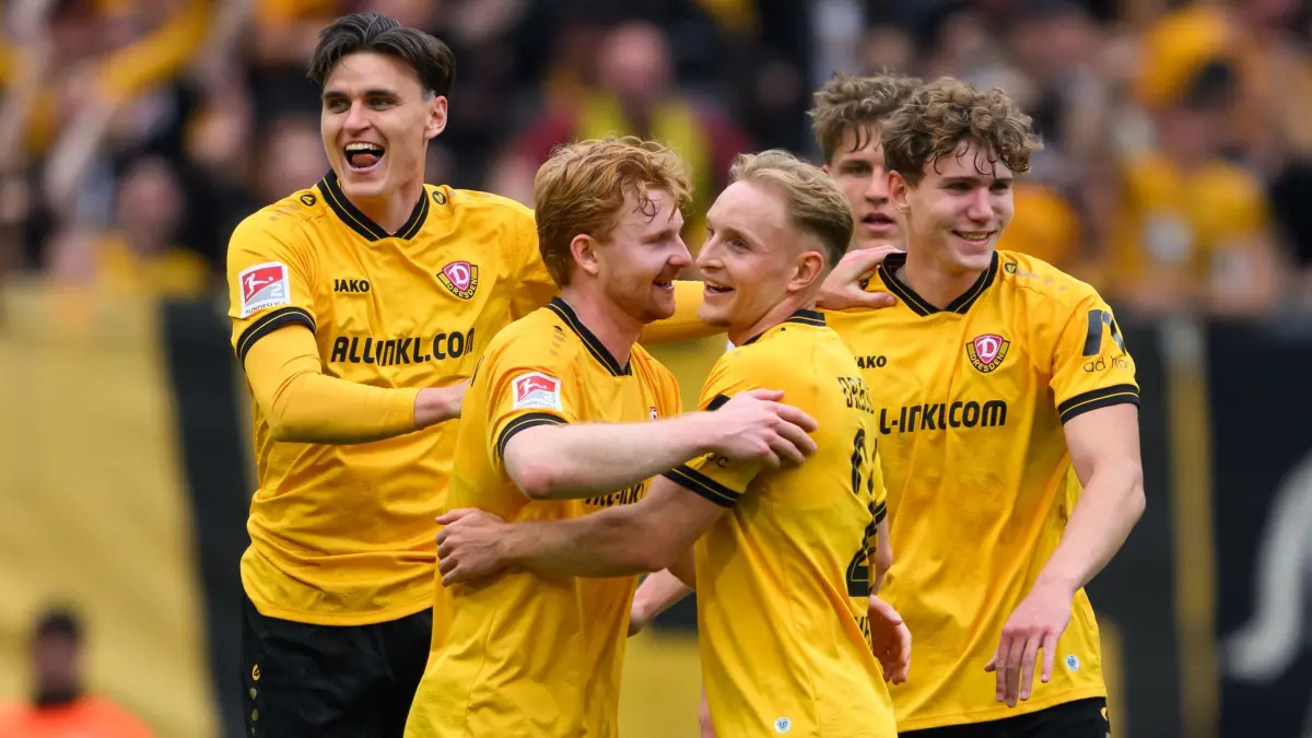 SG Dynamo Dresden - Holstein Kiel: 17.05.2026, Sachsen, Dresden: Fußball, Männer: 2. Bundesliga, SG Dynamo Dresden - Holstein Kiel, 34. Spieltag, Rudolf-Harbig-Stadion, Thomas Keller (Dynamo Dresden, l-r), Robert Wagner (Dynamo Dresden), Tony Menzel (Dynamo Dresden) und Friedrich Müller (Dynamo Dresden) jubeln nach dem Klassenerhalt. Foto: Robert Michael/dpa - WICHTIGER HINWEIS: Gemäß den Vorgaben der DFL Deutsche Fußball Liga bzw. des DFB Deutscher Fußball-Bund ist es untersagt, in dem Stadion und/oder vom Spiel angefertigte Fotoaufnahmen in Form von Sequenzbildern und/oder videoähnlichen Fotostrecken zu verwerten bzw. verwerten zu lassen. +++ dpa-Bildfunk +++