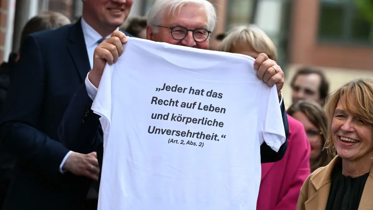 Bundespräsident Frank-Walter Steinmeier in Dorsten: 18.05.2026, Nordrhein-Westfalen, Dorsten: Bundespräsident Frank-Walter Steinmeier hält ein T-Shirt mit dem Artikel 2 des Grundgesetzes. Der Besuch in Dorsten bildet den Auftakt zum bundesweiten Grundgesetz-Ehrentag. Foto: Federico Gambarini/dpa +++ dpa-Bildfunk +++
