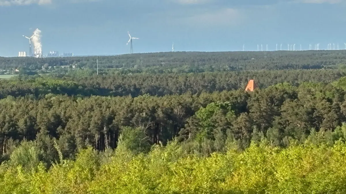 In der rechten Bildmitte ist die rote Kirchturmspitze zu entdecken. Darüber hinaus präsentiert sich das Kraftwerk Jänschwalde am Horizont.
