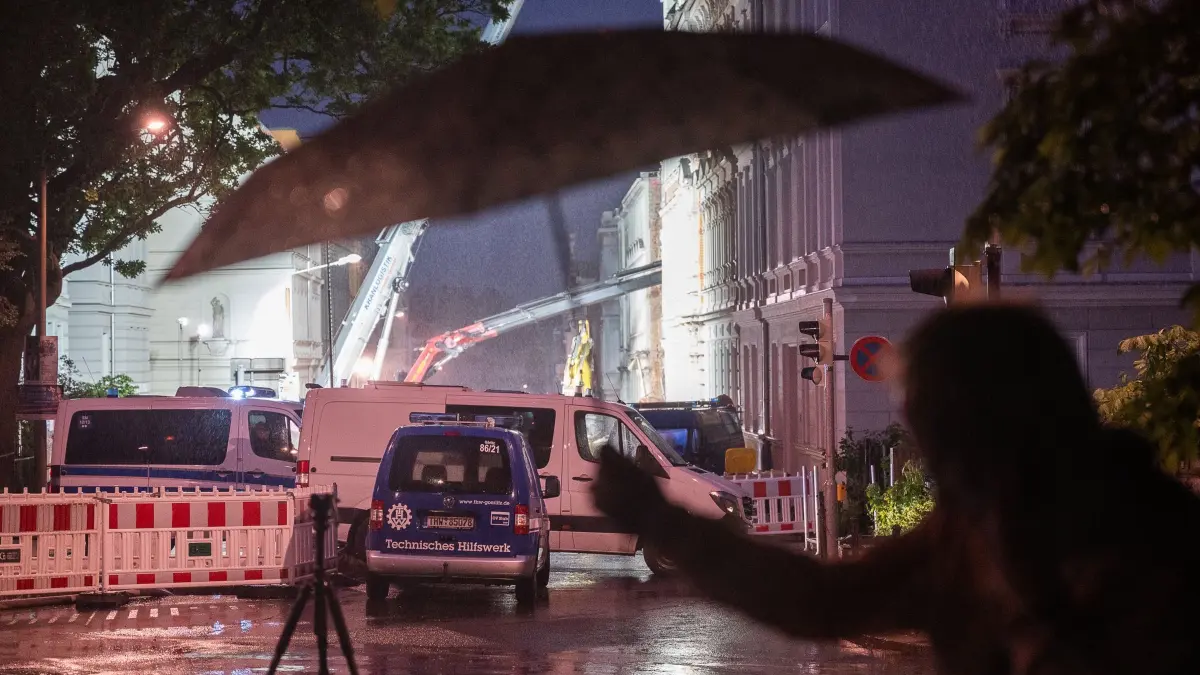 Hauseinsturz in Görlitz: 20.05.2026, Sachsen, Görlitz: Ein Mann hält einen Regenschirm in die höhe vor der Einsatzstelle an der James-von-Moltke-Strasse in Görlitz. Hier kam es am frühen Abend des 18.5.2026 zu einem Einsturz eines bewohnten Hauses. Foto: Paul Glaser/dpa +++ dpa-Bildfunk +++