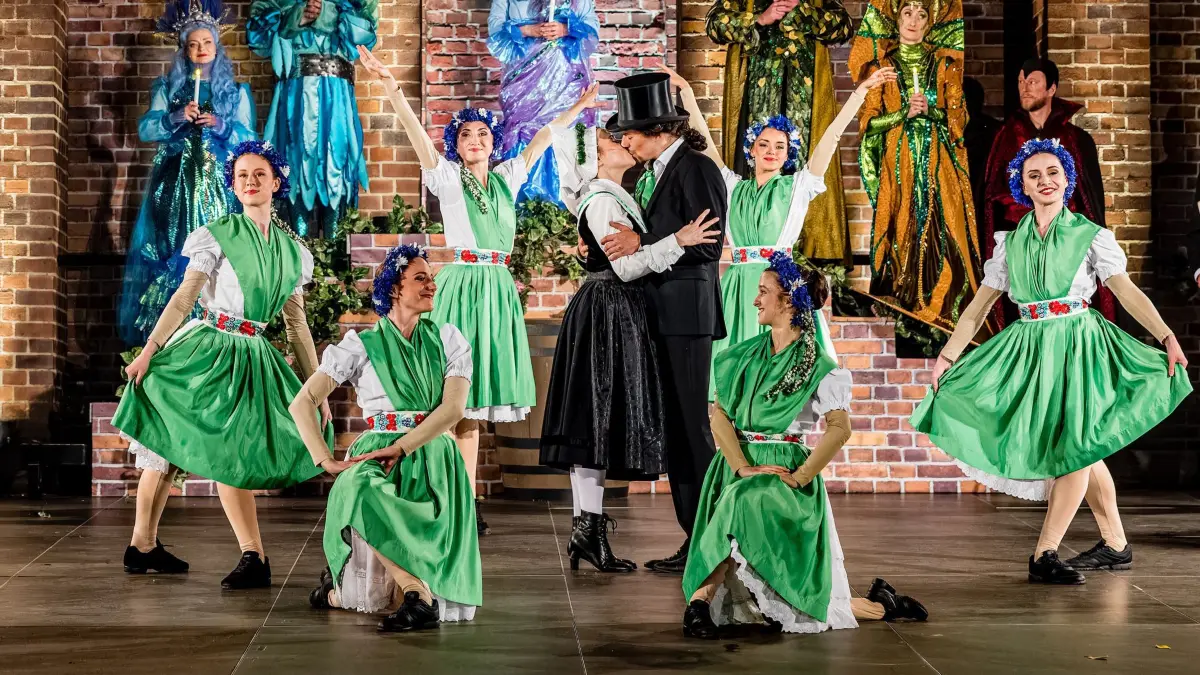 Generalprobe Spreewälder Sagennacht: 22.05.2026, Brandenburg, Burg (Spreewald): Schauspielerinnen und Tänzerinnen des Sorbischen National-Ensemble, in der Mitte Božena Bjarsch als Wanka und Moritz Häusler als Janek, stehen bei der Generalprobe des Stückes «Müschen impossible, oder Wanka, Janek und die drei Unmöglichkeiten» auf der Freilichtbühne am Bismarckturm. Im Mittelpunkt der inzwischen 17. Auflage der Sagennacht steht Wanka, die nicht zulassen will, dass ihre Heimat zerstört wird. Denn der superreiche Unternehmer Dieterich Muks möchte den Spreewald einebnen, um eine riesengroße Fabrik zu errichten. Mit dieser Nachricht platzt er in das fröhliche Müschener Erntedankfest. Was die Menschen zuerst für einen Scherz halten, ist bitterer Ernst. Als sich die Menge dagegen auflehnt, lässt Muks keinen Zweifel daran, dass er seinen Plan mit aller Macht durchsetzen will. Foto: Frank Hammerschmidt/dpa +++ dpa-Bildfunk +++