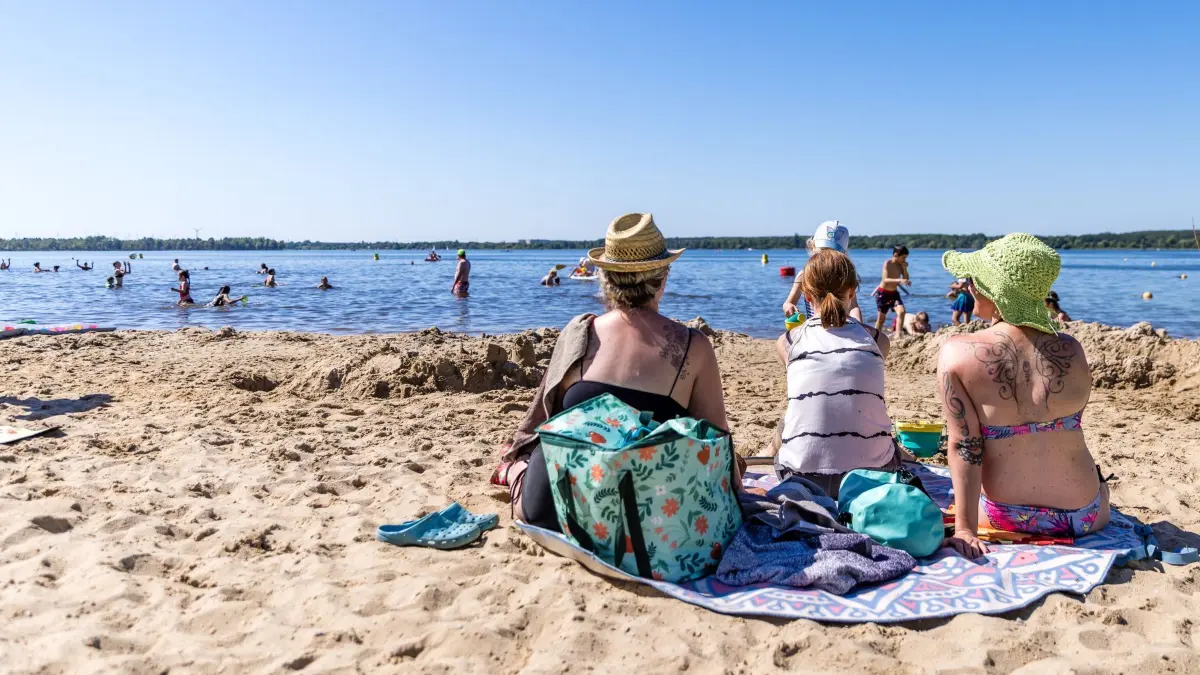 Sommerliches Wetter am Pfingstmontag: 25.05.2026, Brandenburg, Senftenberg: Menschen sitzen am Großkoschener Seestrand und schauen in den Senftenberger See. Die Temperaturen in Südbrandenburg werden heute die 30-Grad-Marke nicht erreichen, die Sonne scheint aber ganztägig und es bleibt trocken. Foto: Frank Hammerschmidt/dpa - ACHTUNG: Verwendung nur im vollen Format +++ dpa-Bildfunk +++