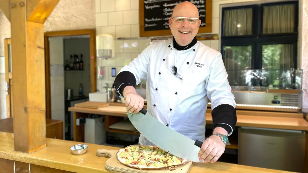 Alexander Tetsch, Chef des Restaurant "Schmeckerlein" in Welzow-Proschim, schneidet am 19.05.2026 einen Flammkuchen in seiner Gartenküche.