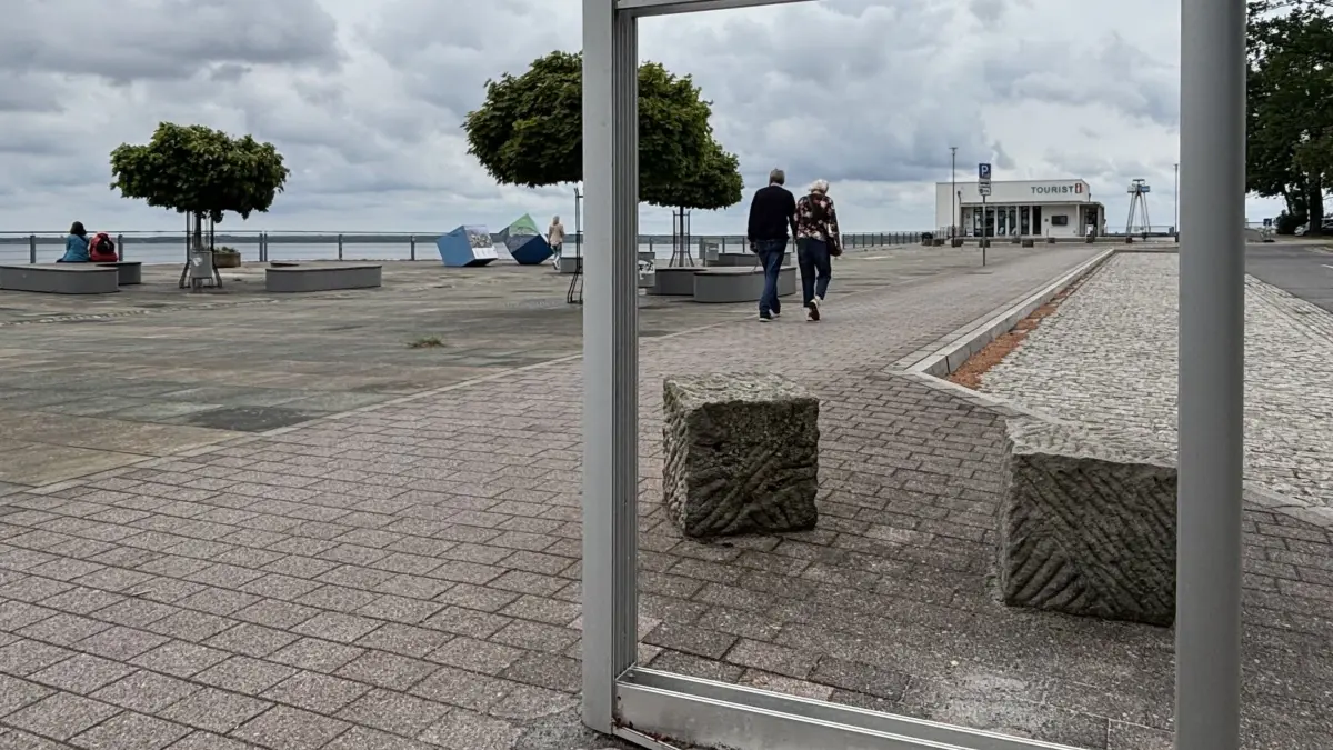 Spaziergänger auf dem Weg zur Touristinfo der Seestadt Großräschen. Wo in den Sommermonaten von 2025 knapp fünf Meter hohe Palmen der Hingucker schlechthin sind, ist aktuell viel Platz.