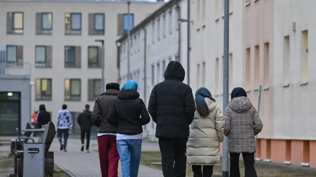 Unterkunft für Asylbewerber: ARCHIV - 14.12.2023, Brandenburg, Eisenhüttenstadt: Migranten gehen über das Gelände der Zentralen Erstaufnahmeeinrichtung für Asylbewerber (ZABH) des Landes Brandenburg in Eisenhüttenstadt. (zu dpa: «Deutschlands Kürzung von Asylleistungen EU-rechtswidrig») Foto: Patrick Pleul/dpa +++ dpa-Bildfunk +++