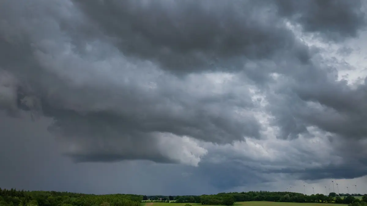 Gewitter über Norddeutschland: ARCHIV - 04.06.2026, Mecklenburg-Vorpommern, Neuendorf: Dunkle Gewitterwolken ziehen über einen Windpark (Luftaufnahme mit Drohne). Der Deutsche Wetterdienst warnt in Mecklenburg-Vorpommern vor Hagel, Sturm und Starkregen. (zu dpa: «Auf einen warmen Wochenbeginn folgen Regen und Gewitter») Foto: Jens Büttner/dpa +++ dpa-Bildfunk +++