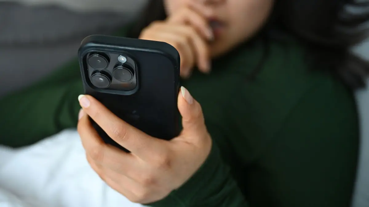 Eine junge Frau liegt mit ihrem Handy auf der Couch: ILLUSTRATION - 01.04.2026, Berlin: Nicht immer seriös: Vereinfachte Checklisten und schnelle Diagnosen auf Social Media können ein verzerrtes Bild psychischer Erkrankungen vermitteln. (zu dpa: «Nacktfotos auf Kinderhandys: London setzt Ultimatum») Foto: Elisa Schu/dpa/dpa-tmn +++ dpa-Bildfunk +++