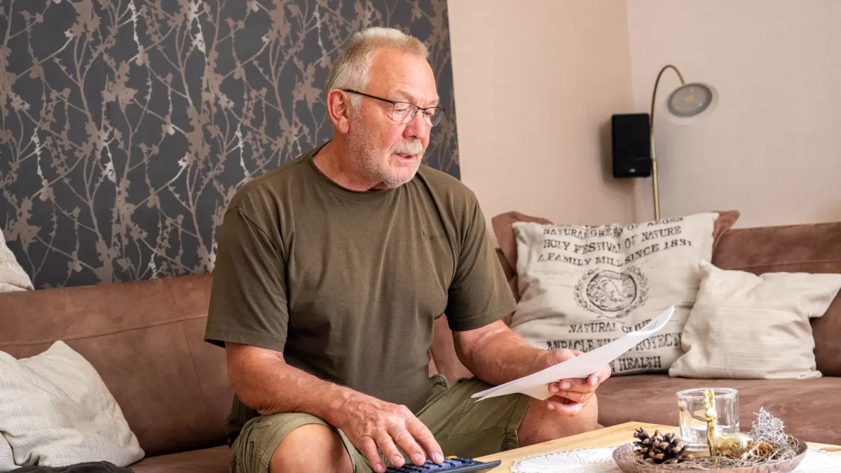 Ein älterer Mann guckt mit Taschenrechner durch Unterlagen: ILLUSTRATION - Witwenrente vor dem Aus? Die Rentenkommission denkt über ein Pflicht-Splitting nach. Klingt gerecht – kann aber für Hinterbliebene finanziell schlechter sein als die Witwenrente. (zu dpa: «Witwenrenten-Aus? Wie sich das finanziell auswirken könnte») Foto: Benjamin Nolte/dpa-tmn - Honorarfrei nur für Bezieher des dpa-Themendienstes +++ dpa-Themendienst +++