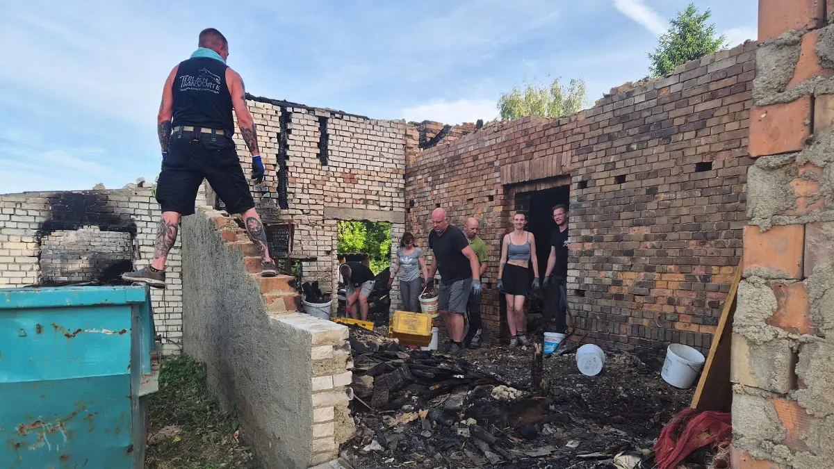 Mitbewohner und Feuerwehrleute treffen sich bei Uwe Schumanski in Saadow und helfen ihm bei den Aufräumarbeiten nach dem Brand.