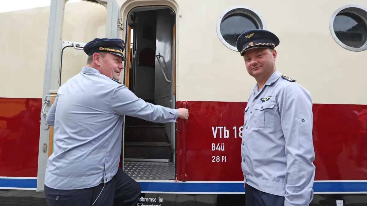 Offizielle Übergabe des restaurierten DDR-Schnellzugs SVT Görlitz: 13.06.2026, Sachsen-Anhalt, Thale: Michael Brandes (l) und Gregor Schulz haben den Zug VT18.16 bei seiner ersten Fahr in einer Reichsbahnuniform begleitet. Nach mehr als 5 Jahren ist der ehemalige DDR-Schnellzug wieder einsatzbereit. Rund 7 Millionen Euro wurden für die Aufbereitung des Zuges aufgewendet. Die Aufarbeitung erfolgte in der VIS Halberstadt. Zur offiziellen Übergabe des restaurierten DDR-Schnellzugs waren am Vormittag hunderte Schaulustige und viele Eisenbahnfans gekommen. Foto: Matthias Bein/dpa +++ dpa-Bildfunk +++
