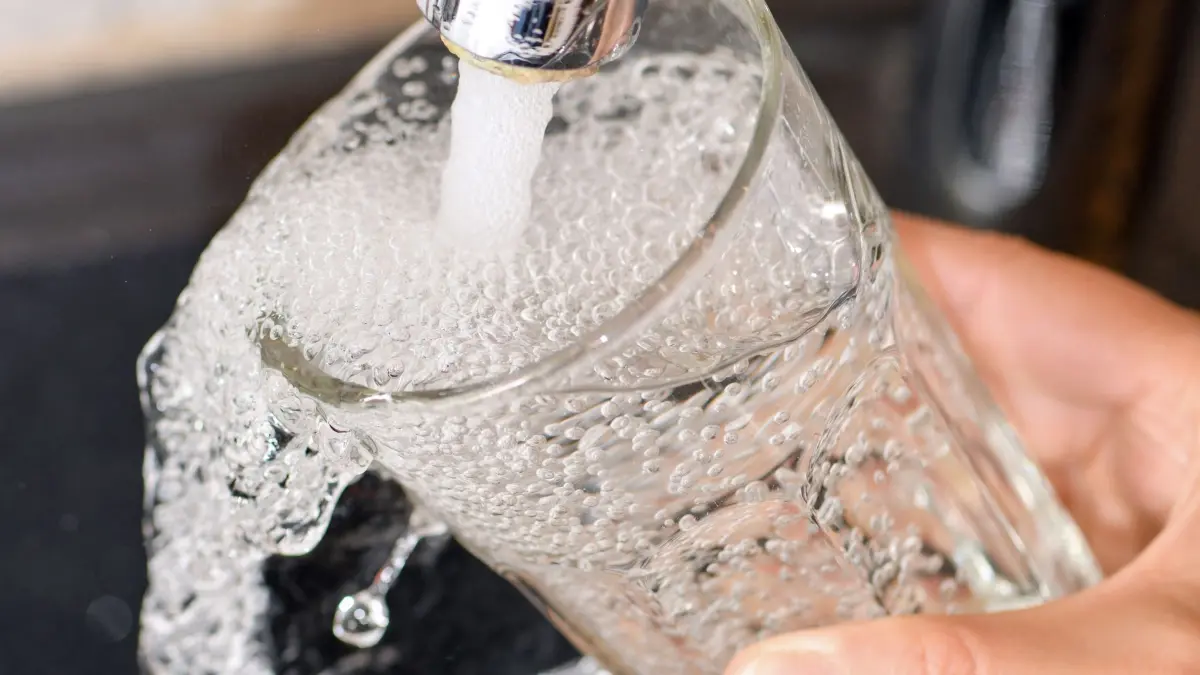 Eine Frau füllt ein Glas mit Trinkwasser aus dem Hahn: ARCHIV - Trinkwasser ist ein Allgemeingut. Es steht jeder Bürgerin und jedem Bürger zu. (zu dpa: «Trinkwasser: Wann dürfen Kommunen den Verbrauch begrenzen?») Foto: Patrick Pleul/dpa-Zentralbild/dpa - Honorarfrei nur für Bezieher des dpa-Themendienstes +++ dpa-Themendienst +++