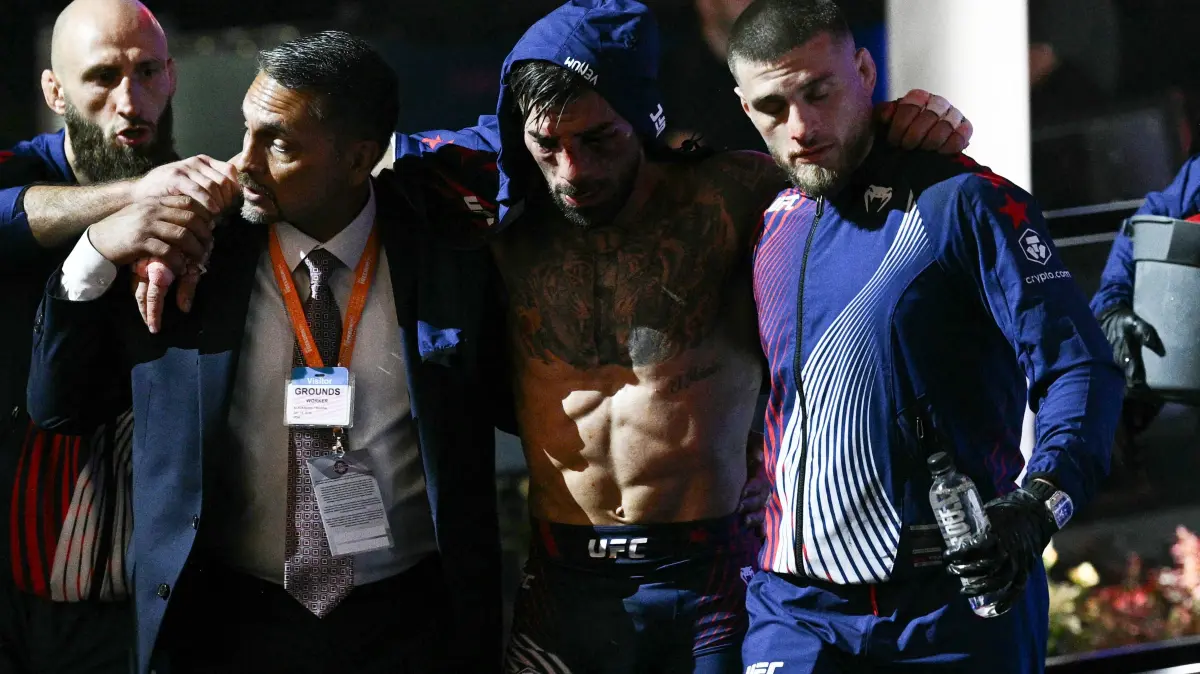 776510421: Aleksandre Topuria (R) assists his brother, Georgia’s Ilia Topuria (C), as they leave after losing the lightweight title bout against US fighter Justin Gaethje during the "UFC Freedom 250" mixed martial arts event on the South Lawn of the White House in Washington, DC, early morning on June 15, 2026. (Photo by Brendan SMIALOWSKI / AFP)