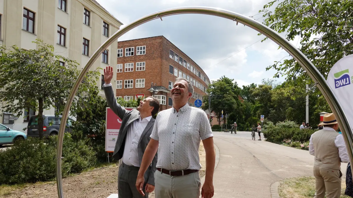 Stadtfest Wassernebeltor: Links: LWG Geschäftsführer Sebastian Lindner, rechts: Oberbürgermeister Tobias Schick (SPD).
Erstes Wassernebeltor sorgt für Erfrischung in Innenstadt
In Cottbus/Chóśebuz ist am Donnerstag ein Wassernebeltor in Betrieb genommen worden. Pünktlich zum Stadtfestwochen- ende (19.06. bis 21.06.2026) steht damit ein neues Angebot für die Erfri- schung im Alltag zur Verfügung. Das Wassernebeltor wurde auf dem Fußweg zum Japanischen Teehäuschen nahe der Töpferstraße errichtet.
Hintergrund sind wärmer werdende Sommer mit Hitzewellen. Daher wachsen gerade in dicht bebauten Innenstädten die Belastungen und Herausforderungen für die Menschen. Mit der Einweihung des neuen Wassernebeltors setzen die Stadt Cottbus/Chóśebuz und die LWG ge- meinsam ein sichtbares Zeichen für neue Lösungen zur Anpassung an den Klimawandel. Dabei muss es nicht zwingend nur um größere Investi- tionen gehen, sondern um auch um kleinere Angebote, die den Men- schen unmittelbar zugutekommen.
Das Wassernebeltor erzeugt einen feinen Wassernebel, der für eine an- genehme Erfrischung sorgt. Besucherinnen und Besucher können das Tor einfach durchqueren und lösen den Wassernebel per Knopfdruck selbst aus. Ermöglicht wurde die Umsetzung mit Mitteln aus dem Verfügungsfonds im Rahmen der Städtebauförderkulisse „Lebendige Zentren – Innenstadt“. Die Gesamtkosten belaufen sich auf ca.
13.000 Euro, von denen die Hälfte die LWG beigesteuert hat.