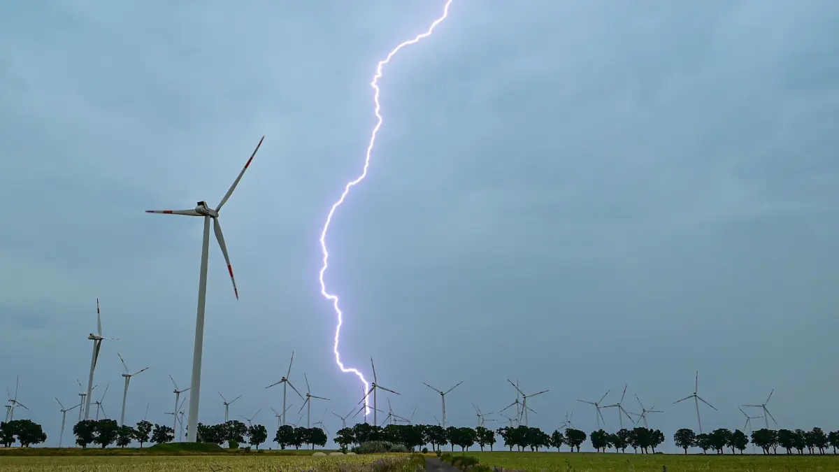 Gewitter über Brandenburg: 20.06.2026, Brandenburg, Petersdorf: Ein Blitz leuchtet vor dunklen Gewitterwolken über der Landschaft mit einem Windenergiepark im östlichen Brandenburg. Foto: Patrick Pleul/dpa +++ dpa-Bildfunk +++