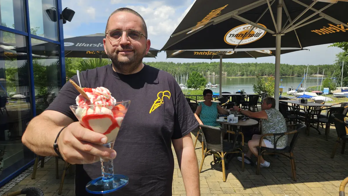 André Bömke, Servicekraft der "Eispause" im Hafencamp, präsentiert einen Eisbecher. Neben 16 Eissorten gehören auch hausgemachte Limonaden zu den Spezialitäten des beliebten Stopps am Seeufer.