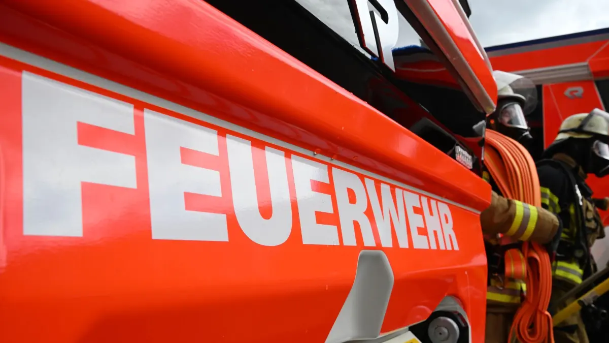 Feuerwehr: PRODUKTION - 11.06.2026, Baden-Württemberg, Stuttgart: Zwei Feuerwehrleute gehen mit ihrer Ausrüstung zur Brandbekämpfung an einem Einsatzfahrzeug vorbei (gestellte Szene). (zu dpa: «Kurzzeitiger Stromausfall in Ludwigsburg») Foto: Bernd Weißbrod/dpa +++ dpa-Bildfunk +++