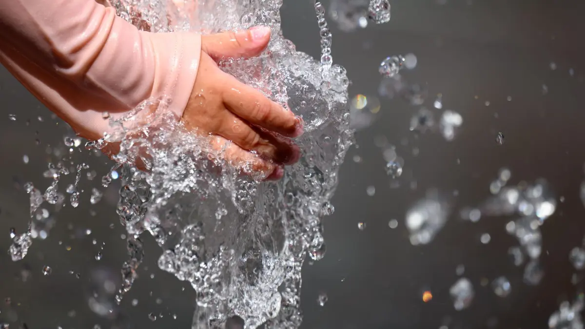 Sommerwetter in Sachsen: 24.06.2026, Sachsen, Chemnitz: Ein kleines Mädchen erfrischt sich in einem Wasserspiel in einer Fußgängerzone in Chemnitz. In Sachsen zeigt sich heute überall die Sonne mit hohen Temperaturen über 30 Grad. Foto: Hendrik Schmidt/dpa +++ dpa-Bildfunk +++