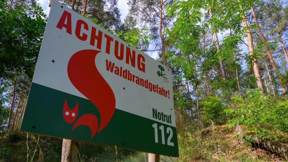 Hitze in Deutschland - Waldbrandgefahr in Brandenburg: 25.06.2026, Brandenburg, Peitz: Ein Warnschild mit der Aufschrift «Achtung Waldbrandgefahr! Notruf 112» vom Landesbetrieb Forst Brandenburg steht an einem Waldrand im südlichen Brandenburg. Mit den steigenden Temperaturen hat in Brandenburg die Gefahr von Waldbränden stark zugenommen. Foto: Patrick Pleul/dpa +++ dpa-Bildfunk +++