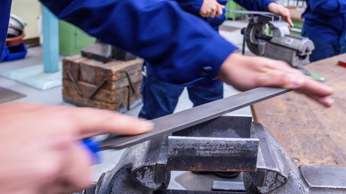 Lehrlinge arbeiten mit der Metallfeile an Schraubstöcken in einer Lehrwerkstatt. Lehrling, Geselle, Meister: Die Ausbildung in Deutschland wird weltweit geschätzt. Auch in Großbritannien. Doch im Königreich werden Ausbildungsberufe noch immer stiefmütterlich behandelt. (zu dpa "Deutsche Wirtschaft in London will Ausbildung nach deutschem Vorbild") +++ dpa-Bildfunk +++