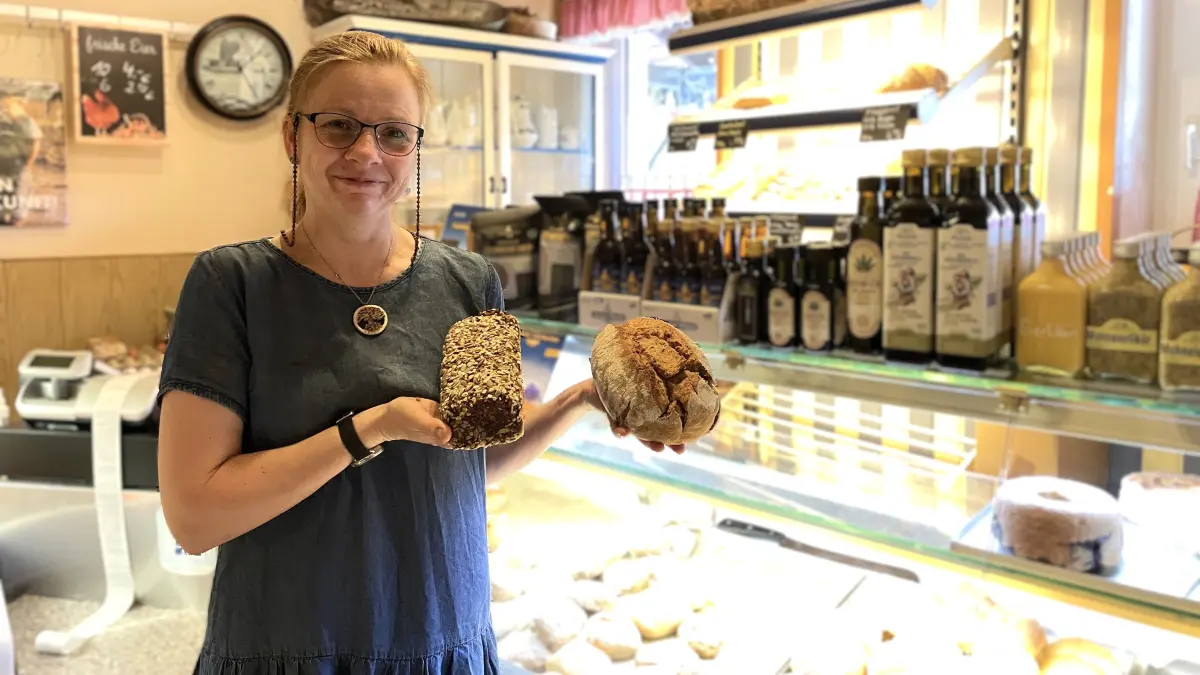 Liane Dörry steht am 25.06.2026 mit zwei Broten in der Hand in ihrem Hofladen "Der kleine Hof Dörry" in Spremberg-Hornow.