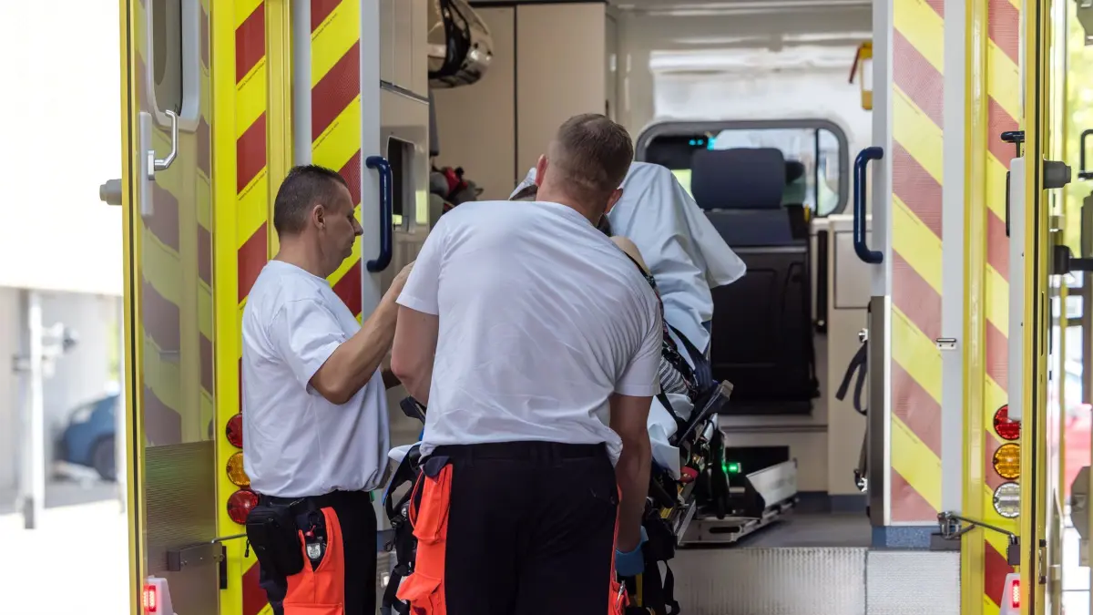 Hitze in Südbrandenburg: 28.06.2026, Brandenburg, Cottbus: Rettungssanitäter heben an der Notaufnahme der Medizinischen Universität Lausitz - Carl Thiem eine Trage mit einer Patientin aus ihrem Rettungswagen. Zurzeit sind verstärkt Rettungseinsätze wegen hitzebedingter Beschwerden erforderlich. Auch am heutigen Sonntag werden in der Region Temperaturen um die 40 Grad Celsius erwartet. Foto: Frank Hammerschmidt/dpa +++ dpa-Bildfunk +++
