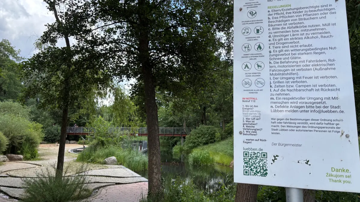 Blick auf Wasserspielplatz mit der Tafel zur Platzordnung.