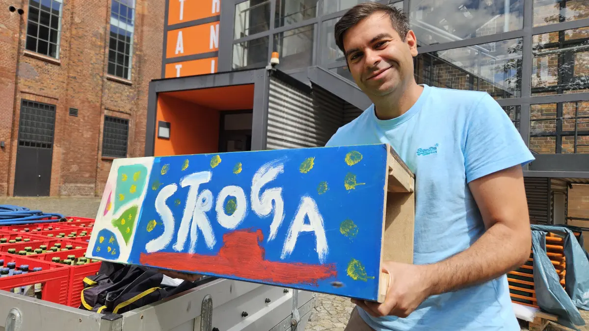 Mario Douadi vom Stroga Festival e.V. zeigt die selbst gestaltete Spendenbox des Festivals. Die Veranstalter hoffen auf mehr Unterstützung und Ticketverkäufe, damit das Event in Knappenrode auch über 2026 hinaus eine Zukunft hat.
