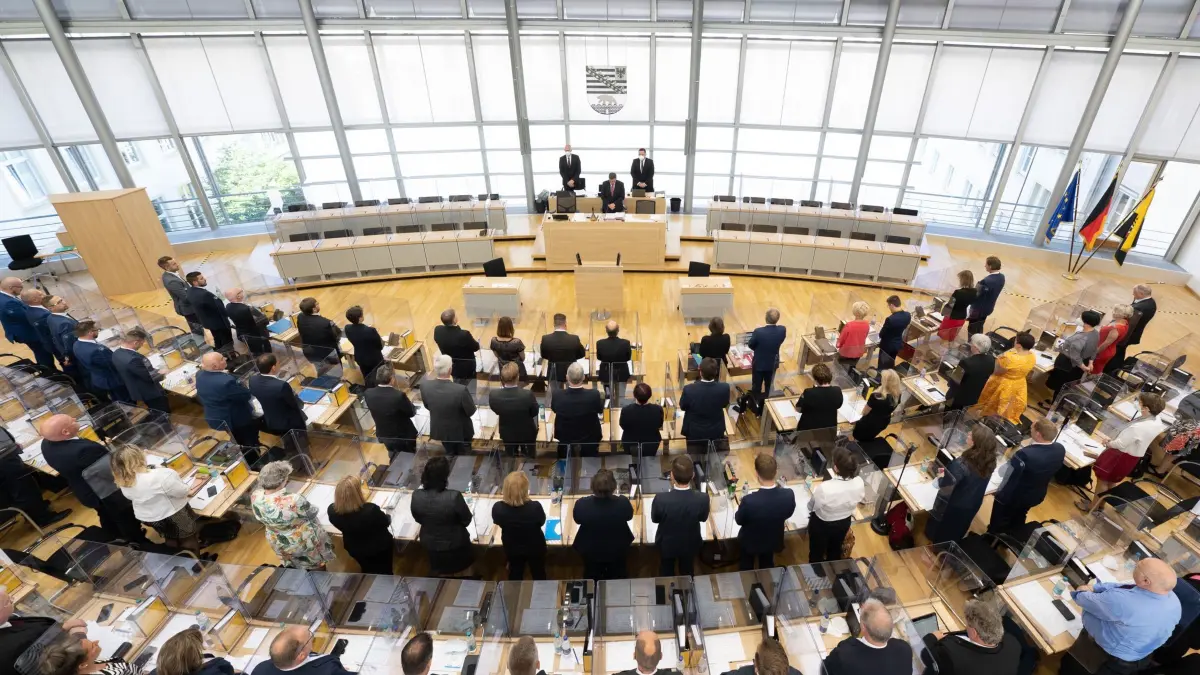 Landtag Sachsen-Anhalt: ARCHIV - 06.07.2021, Sachsen-Anhalt, Magdeburg: Die Abgeordneten stehen im Rahmen der konstituierenden Sitzung des Landtags während einer Gedenkminute für die Opfer der Corona-Pandemie im Plenum. In fünf Jahren der Wahlperiode war die Beteiligung einzelner Abgeordneter sehr unterschiedlich. (zu dpa: «Die Lauten und die Leisen: Ein Rückblick auf fünf Jahre Landtag») Foto: Sebastian Kahnert/dpa-Zentralbild/dpa +++ dpa-Bildfunk +++