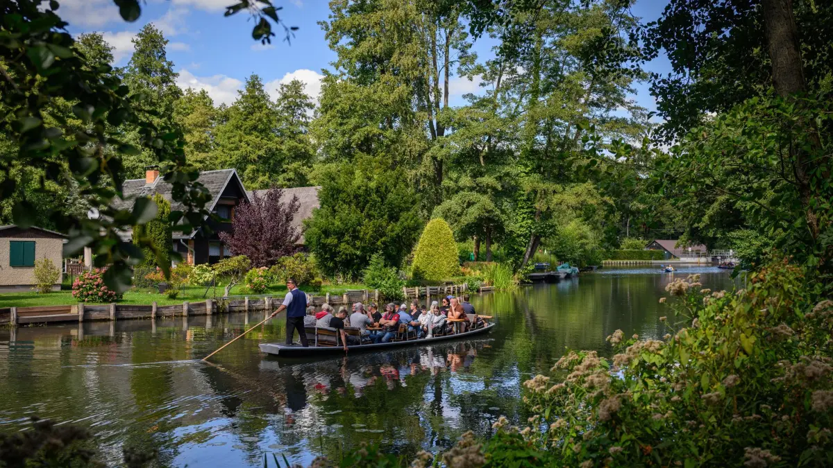 Touristen unternehmen eine Fahrt in einem Kahn im Spreewald: ARCHIV - Ein Fährmann schiebt einen Kahn durch eines der zahlreichen Fließe im Spreewald - ein bisschen wie Venedig, nur ohne den Trubel. (zu dpa: «Sieben Orte, die Fernweh stillen – ganz ohne Flug») Foto: Patrick Pleul/dpa/dpa-tmn - Honorarfrei nur für Bezieher des dpa-Themendienstes +++ dpa-Themendienst +++