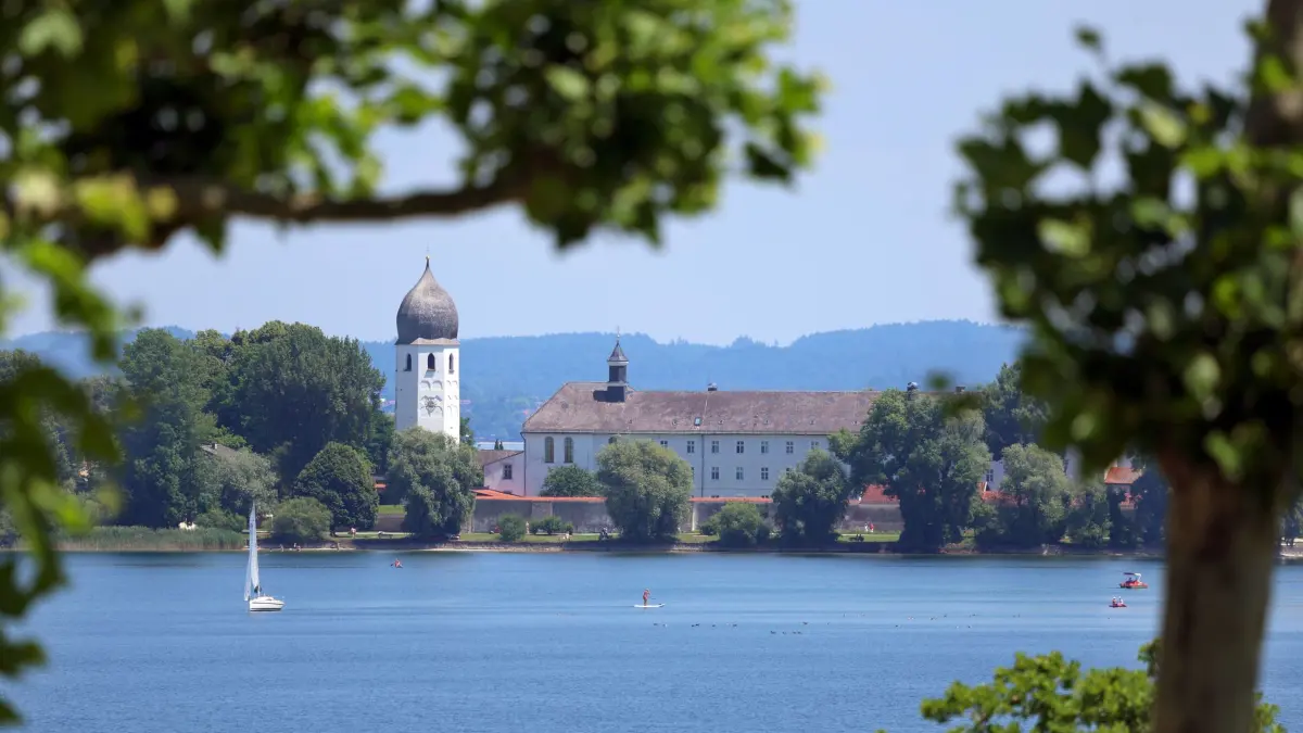 Wetter am Chiemsee: PRODUKTION - 18.06.2025, Bayern, Chiemsee: Ein Stand Up Paddler (SUP) gleitet im Sonnenschein vor der Fraueninsel über den Chiemsee. (zu dpa: «Rauch auf Chiemsee-Schiff - Fahrgäste müssen von Bord») Foto: Karl-Josef Hildenbrand/dpa +++ dpa-Bildfunk +++