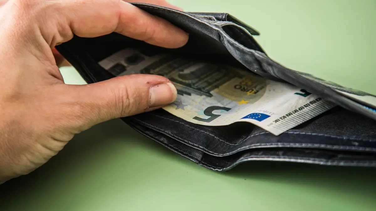 Portemonnaie aus Leder mit 5-Euro-Schein: ILLUSTRATION - Arbeitnehmer haben ein Recht auf pünktliche Zahlung des Gehalts. (zu dpa: «Was tun, wenn das Gehalt nicht kommt?») Foto: Christin Klose/dpa-tmn - Honorarfrei nur für Bezieher des dpa-Themendienstes +++ dpa-Themendienst +++