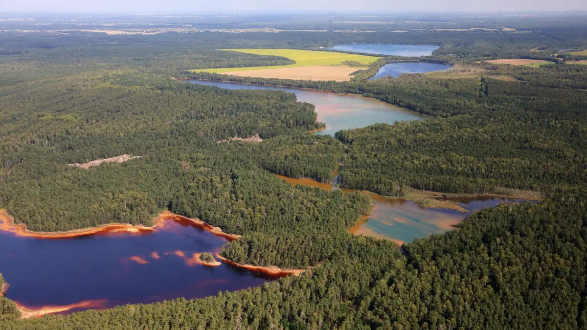 Während sich die Natur die ehemalige Bergbaulandschaft nördlich von Lauchhammer zurückgeholt hat, sind die Tagebaurestseen unwirtlich. Das Wasser ist braun und sauer. Im Vordergrund das Restloch 107 nordöstlich von Plessa.