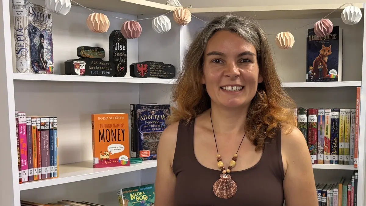 Bibliotheksmitarbeiterin Birgit Stähr freut sich auf viele Leseratten in der Sommerzeit. Im Lesesommer-Regal hinter ihr fallen die Briketts ins Auge. Was es damit wohl auf sich hat?