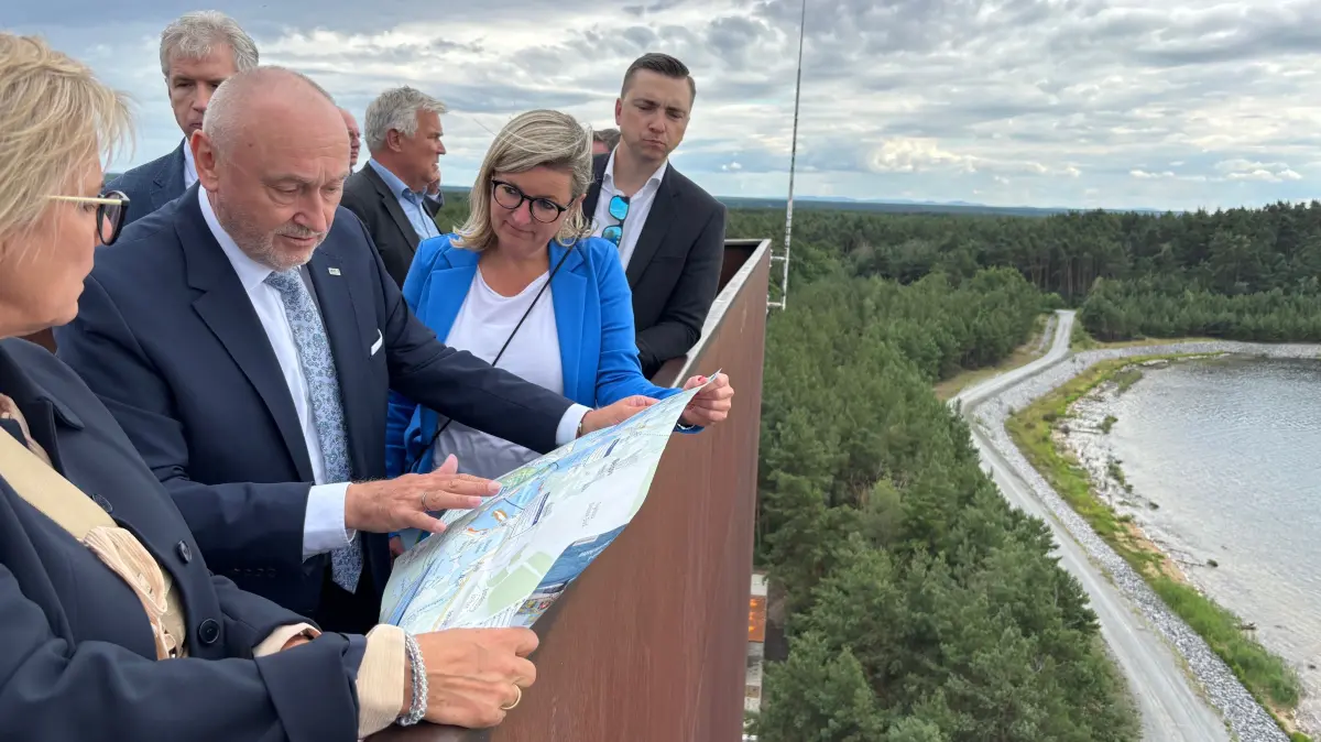 LMBV-Geschäftsführer Bernd Sablotny erklärt den beiden Ministerinnen Barbara Klepsch (l.) und Martina Klement anhand einer Landkarte die Aussicht vom Rostigen Nagel.