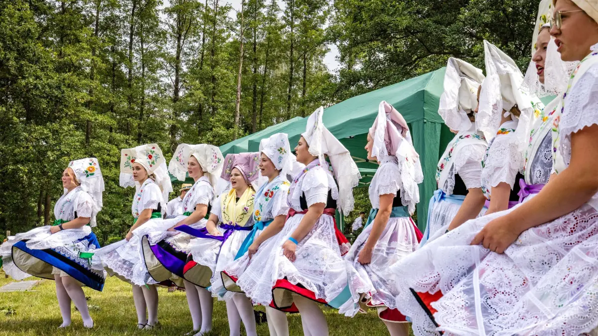 Hahnrupfen beim Burger Erntefest: 26.07.2026, Brandenburg, Burg: Junge Frauen in sorbisch-wendischen Trachten tanzen beim traditionellen sorbisch-wendischen Hahnrupfen beim Erntefest im Spreewald. Beim Hahnrupfen versuchen Reiter von ihrem Pferd aus, einem an einer Stange hängenden toten und ausgebluteten Hahn den Kopf abzureißen. In vielen sorbisch-wendischen Dörfern werden die Erntekönige beim Hahnrupfen ermittelt. In einigen Wochen treten die jeweiligen Sieger aus den Dörfern der Lausitz beim Super-Hahnrupfen gegeneinander an. Foto: Frank Hammerschmidt/dpa +++ dpa-Bildfunk +++