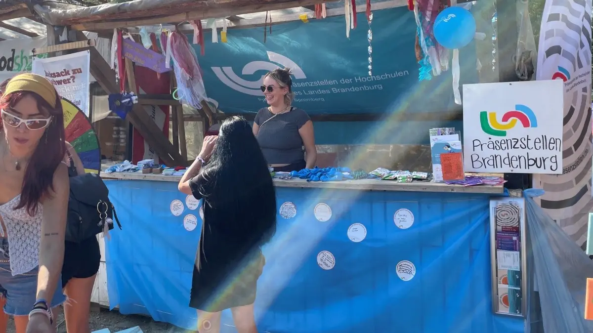 Linda hinter dem Tresen ist selbst bei der BTU Cottbus-Senftenberg angestellt. Sie erklärt, dass Einrichtungen wie TH Wildau, Universitäten Cottbus und Potsdam, FH Potsdam und HNE Eberswalde mit Festivalbesuchern das Gespräch suchen.