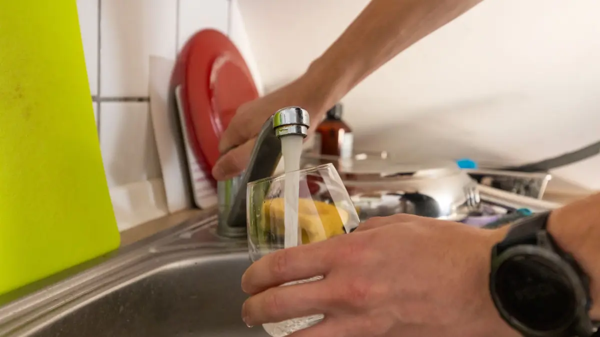 Wohnen unter dem Dach bei Hitze: PRODUKTION - 28.07.2026, Hessen, Marburg: Chemie- und Informatikstudent Johannes Wichert füllt sich ein Glas mit kühlem Wasser in der WG-Küche im Dachgeschoss (gestellte Aufnahme). Foto: Christian Lademann/dpa +++ dpa-Bildfunk +++