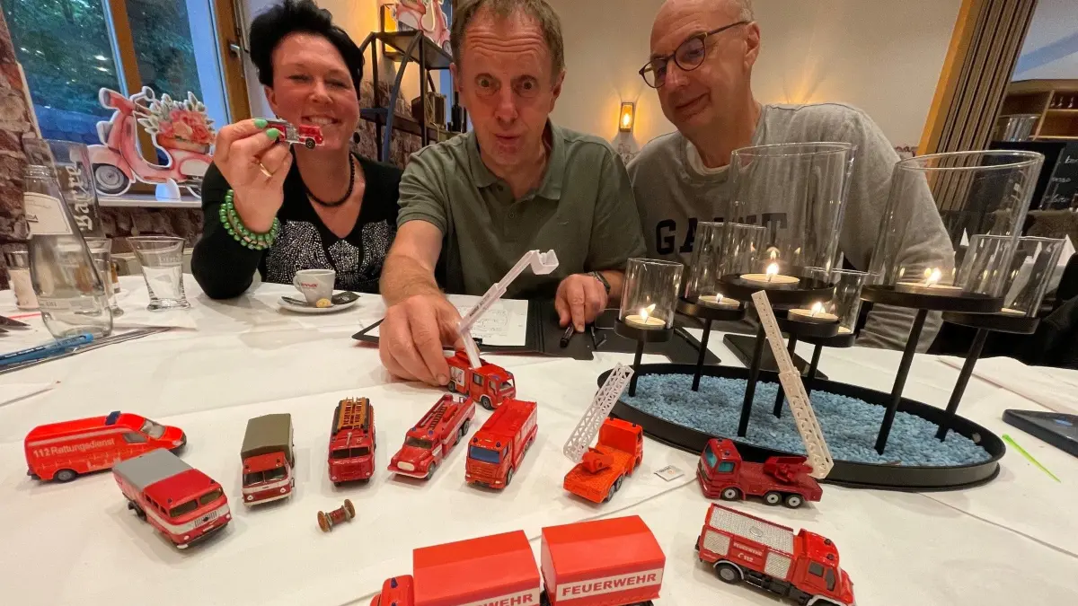 Ideenschmiede mit viel Humor schon am Tisch: Zeichner Jens Thiere wird das Thema Feuerwehren zum Titelbild des neuen Lions-Adventskalenders machen. In kleiner Runde, hier die Lions-Mitglieder Tina Neustadt und Thomas Körlin (r.), sind lustige Episoden, die das winterlich-weihnachtliche Kalenderblatt zieren sollen, zusammengetragen worden.