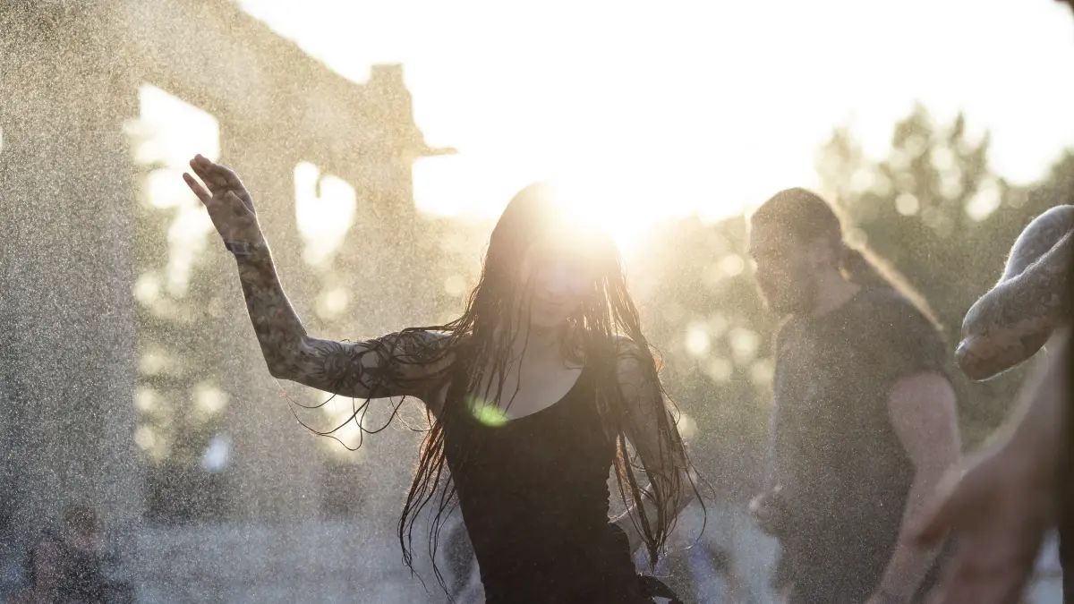 2022: Eine Besucherin tanzt im Sonnenuntergang bei 30°C im Wassernebel auf dem Full Force Festival in Ferropolis (Sachsen-Anhalt).