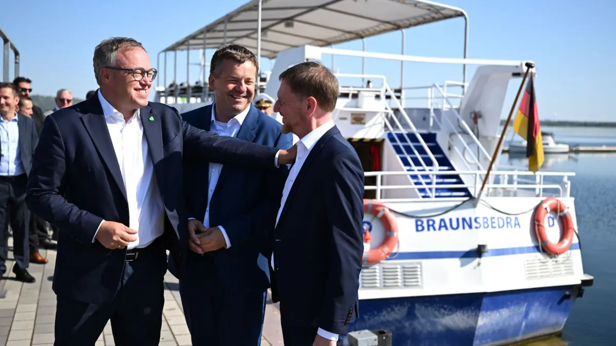 Ministerpräsidenten zu Austausch im Mitteldeutschen Revier: 30.07.2026, Sachsen-Anhalt, Braunsbedra: Mario Voigt (CDU, v.l.), Ministerpräsident von Thüringen, Sven Schulze (CDU), Ministerpräsident von Sachsen-Anhalt, und Michael Kretschmer (CDU), Ministerpräsident von Sachsen, unterhalten sich vor Beginn einer gemeinsamen Bootsfahrt am Geiseltalsee. Im Mittelpunkt des Treffens steht der Strukturwandel in der Region. Foto: Hendrik Schmidt/dpa +++ dpa-Bildfunk +++