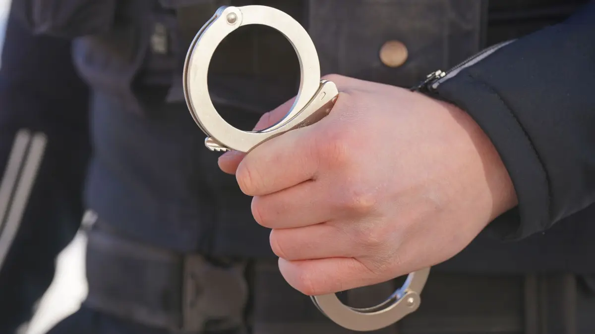 Verdächtiger festgenommen: ARCHIV - 18.01.2024, Mecklenburg-Vorpommern, Schwerin: ILLUSTRATION - Ein Polizist hält Handschellen in der Hand. (zu dpa: «Mann soll Kinder in Schwimmbad missbraucht haben») Foto: Marcus Brandt/dpa +++ dpa-Bildfunk +++