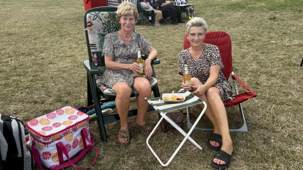 Simone und Katrin machen es sich auf Gartenstühlen bequem.