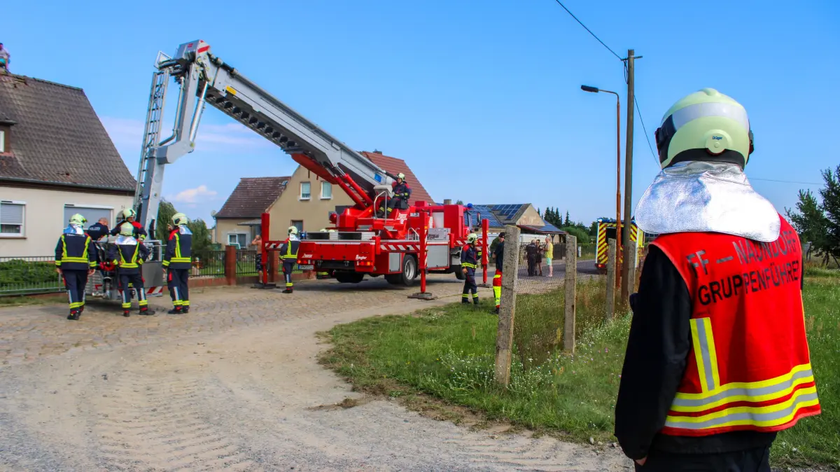 Feuerwehr und Polizei bei einem Einsatz in Neu Sacro im Landkreis Spree-Neiße nach einem Vorfall auf dem Dach eines Wohnhauses.