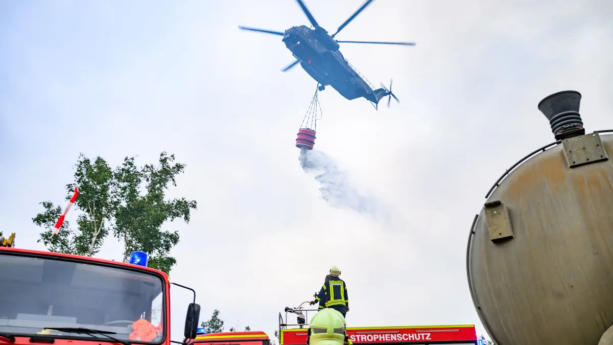 Ein Löschhubschrauber der Bundeswehr und Kräfte der Feuerwehr bei einem Einsatz in Gohrischheide im vergangenen Jahr. Brandenburg ist stark von Waldbränden betroffen. Auch deshalb wurde 2025 das Waldbrandkompetenzzentrum in Wünsdorf eingerichtet. (Archovbild)