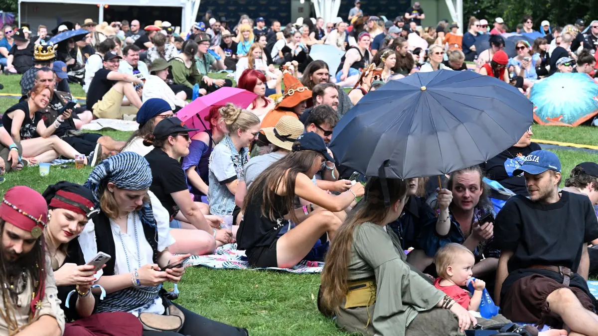 Elbenwald FestivaL 2026: Spannung bei der traditionellen Quiz-Show auf der Hauptbühne am Nachmittag.
Elbenwald Festival im Spreeauenpark.
Der Spreeauenpark in Cottbus verwandelt sich am Wochenende wieder in eine Fantasiewelt mit Fantasy, Musik, Cosplay, Gaming und zahlreichen Mitmachangeboten. Bereits am Donnerstag und Freitag reisten viele Camper aus ganz Deutschland zum diesjährigen Elbenwald Festival an, dass offiziell am Freitag startete und bis Sonntag läuft.
Musikalisch gehören dArtagnan, Fiddler’s Green, Corvus Corax, Punk Rock Factory und Liedfett zu den bekannten Namen, die an drei Tagen im Spreeauenpark auftreten. Den traditionellen Abschluss übernimmt das Pilsen Philharmonic Orchestra mit epischer Musik aus Fantasy, Gaming und Kino. Dazu kommen Cosplay Wettbewerbe, Lesungen, Shows, Workshops, Schwertkampf, Bogenschießen, historische Tänze, Gaming, Tabletop, Rollenspiel, Karaoke, Bogenshießen und zahlreiche weitere Angebote zum Mitmachen. Auch regionale Beteiligte wie My Wife and the Microwave, der Dice Club Cottbus und die Ompah Kunstreitshow stehen im Programm.