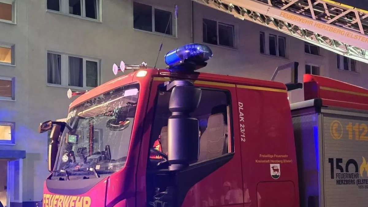 Ein Einsatzwagen der Feuerwehr Herzberg steht vor einem Mehrfamilienhaus, eine Leiter führt in eine Wohnung im Obergeschoss – ein Beispiel für die zunehmenden Hilfeleistungen in Wohngebieten.