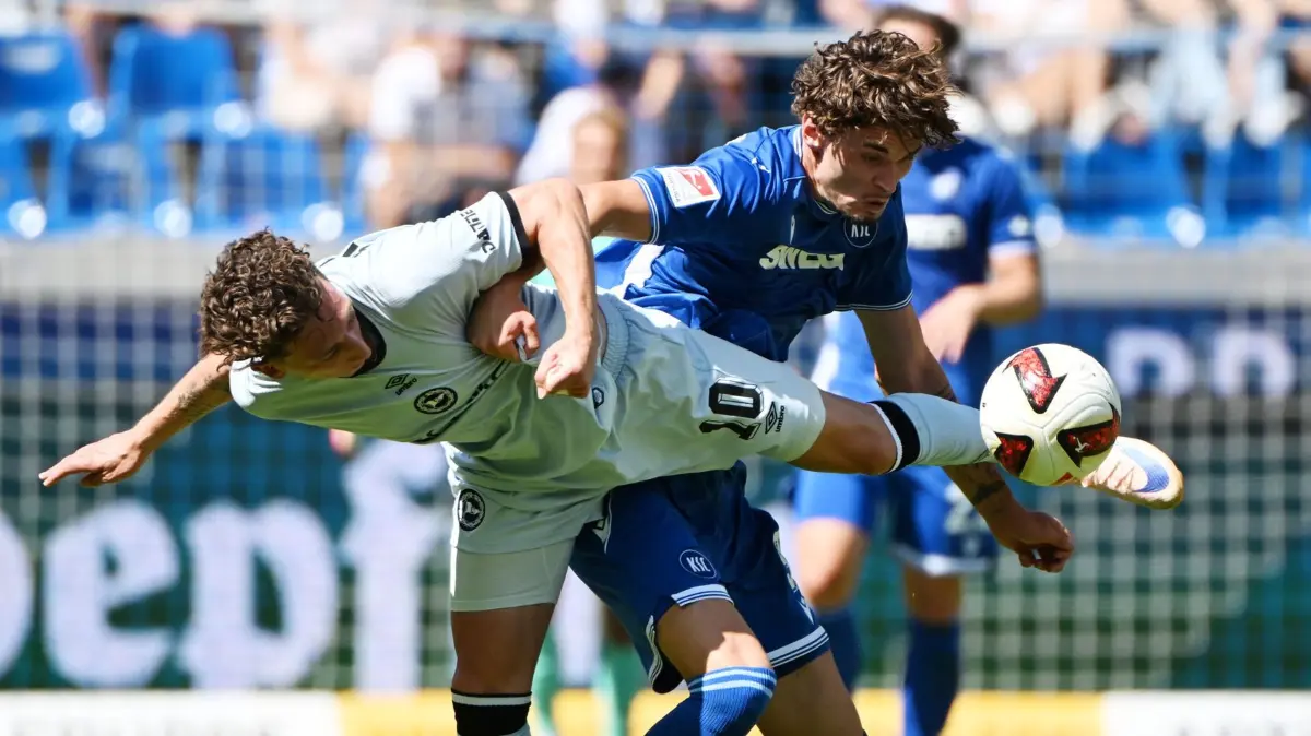 Karlsruher SC - Arminia Bielefeld: 08.08.2026, Baden-Württemberg, Karlsruhe: Fußball, Männer: 2. Bundesliga, Karlsruher SC - Arminia Bielefeld, 1. Spieltag, BBBank Wildpark. Der Karlsruher Moritz Broschinski (r) und der Bielefelder Jannik Rochelt kämpfen um den Ball. Foto: Uli Deck/dpa - WICHTIGER HINWEIS: Gemäß den Vorgaben der Bundesliga bzw. des DFB Deutscher Fußball-Bund ist es untersagt, in dem Stadion und/oder vom Spiel angefertigte Fotoaufnahmen in Form von Sequenzbildern und/oder videoähnlichen Fotostrecken zu verwerten bzw. verwerten zu lassen. +++ dpa-Bildfunk +++